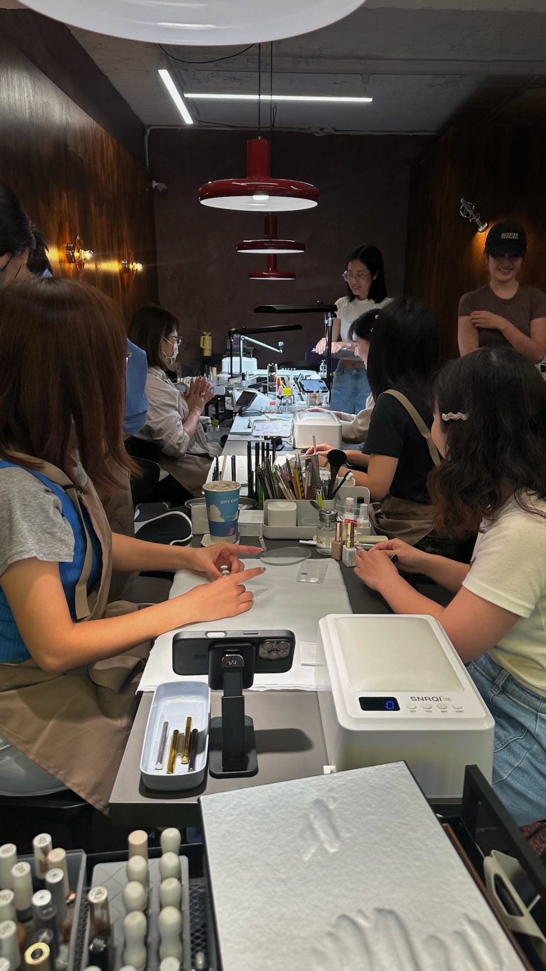 學員圍坐工作桌前練習，桌上擺放美甲工具